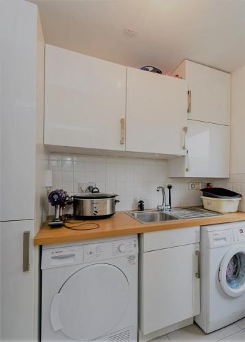 cocina con armarios blancos, fregadero y lavavajillas en Thomas Place, en Dublín