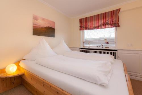 2 weiße Betten in einem Zimmer mit Fenster in der Unterkunft Sylter Sonne, Alt Westerland in Westerland