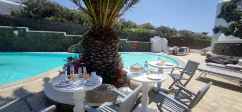 - une piscine avec des tables et des chaises à côté d'un palmier dans l'établissement Mykonian Iros Suites & Villas, à Kalo Livadi