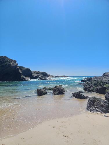 a sandy beach with rocks in the water at Casa Mali in Quinta do Conde