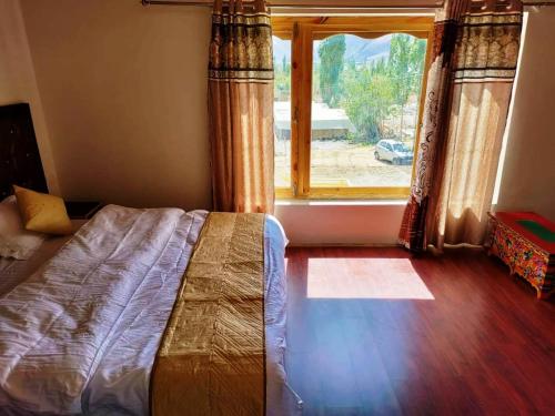 a bedroom with a bed in front of a window at Hotel Nubra Delight and Camps in Hundar