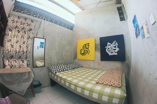 a small bedroom with a bed and a mirror at Condro Wulan Hostel in Malang