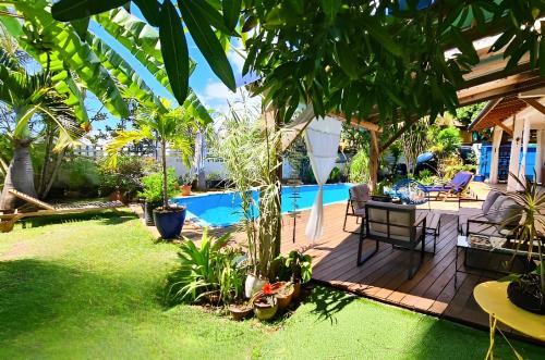 einen Hinterhof mit einer Terrasse und einem Pool in der Unterkunft Ti case fleurie * Piscine * Jardin tropical in Saint-Leu