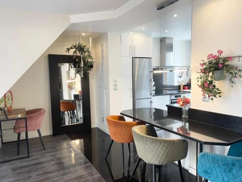 a kitchen with a counter with chairs and a refrigerator at Bohème & Chic à 20' de paris in Savigny-sur-Orge