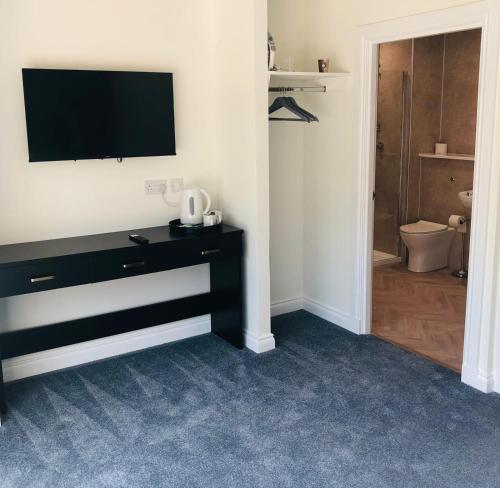 a bathroom with a black dresser with a television on a wall at The Gilvenbank Hotel in Glenrothes