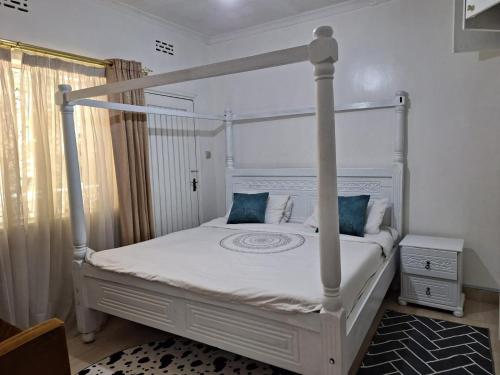 a bedroom with a white canopy bed with blue pillows at 6th Avenue Court in Nairobi
