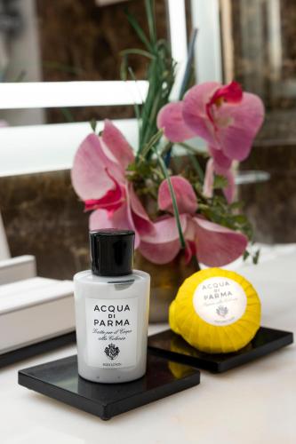 a bottle of apollo parma on a table with flowers at The First Arte - Preferred Hotels & Resorts in Rome
