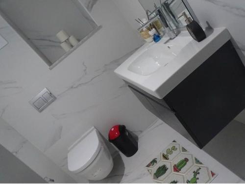 a white bathroom with a sink and a toilet at La perle rare in Monastir