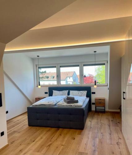 a bedroom with a large bed and two windows at Penthouse Alpenblick in Kempten