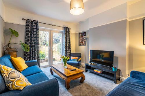 a living room with a blue couch and a tv at Lovely 4BDR home- Off street parking sleeps 7 in Nottingham