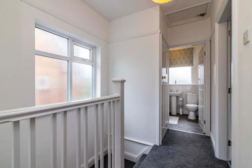 a hallway with a bathroom with a toilet and a window at Lovely 4BDR home- Off street parking sleeps 7 in Nottingham