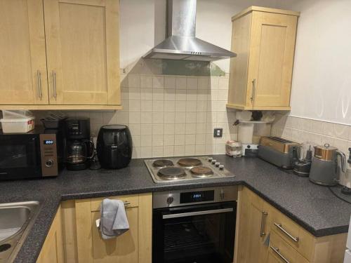 a kitchen with wooden cabinets and a stove top oven at Cute and cosy in Liverpool