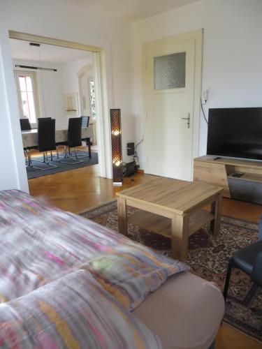 Habitación con cama, mesa y sala de estar. en Chez Carole (4 pièces), en Neuchâtel