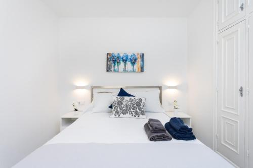 Un dormitorio con una cama blanca con dos zapatos. en Home2Book Comfy Apartment Las Galletas Beach, en Las Galletas