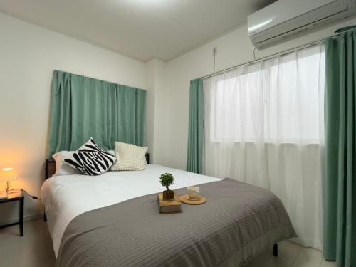 a bedroom with a large bed with green curtains at Relax House in Tokyo