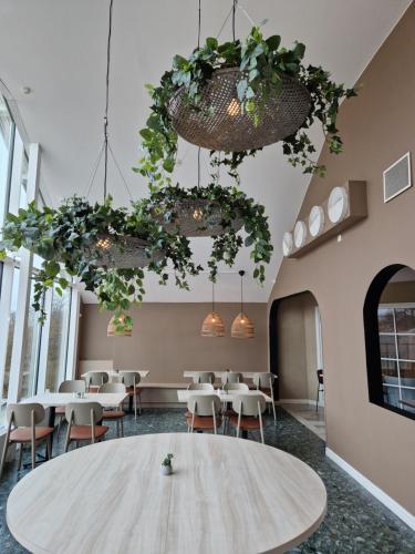 a room with tables and chairs and potted plants at Hotell Erikslund in Ängelholm