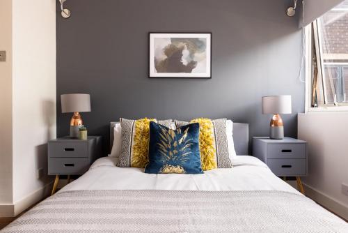 ein Schlafzimmer mit einem Bett mit Kissen und zwei Nachttischen in der Unterkunft The Fitzrovia Collection in London