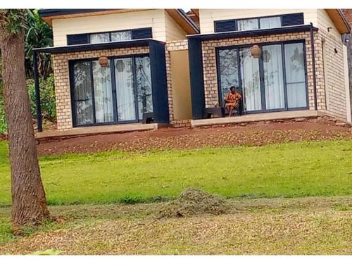 a person sitting on a bench in front of a house at Eben Lake Kivu cottages and Villas in Kagano