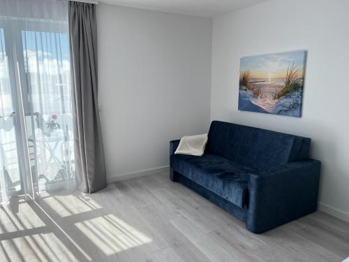 a blue couch in a living room with a window at Srebrna Wydma Resort in Dąbki