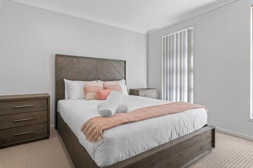 1 dormitorio blanco con 1 cama grande con almohadas rosas en Hunter Explorer - Games Room & Spa, en Cessnock