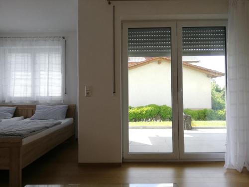 a bedroom with a bed and a sliding glass door at Ferienwohnungen Weishaupt in Meckenbeuren