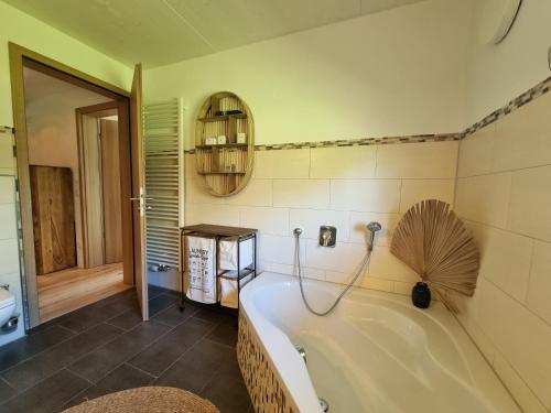 ein Bad mit einer Badewanne und einem Ventilator an der Wand in der Unterkunft Boutique Ferienhaus Chiemsee in Übersee