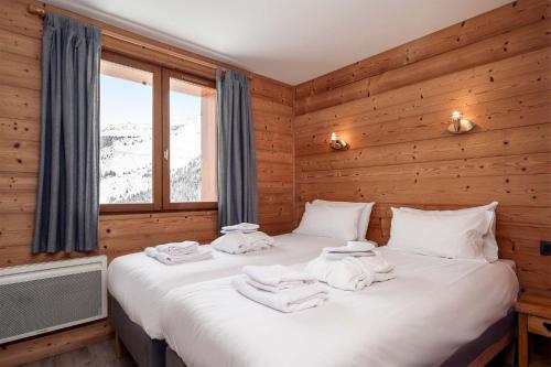 2 camas en una habitación con paredes de madera en Madame Vacances Chalet L'Arclusaz, en Les Allues