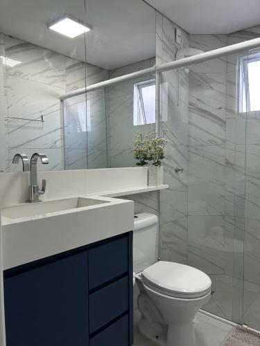 a bathroom with a toilet and a sink and a mirror at Apto 28A - Residencial Palladium Centro, Penha SC in Penha