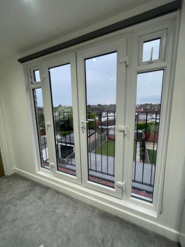 een kamer met glazen deuren en een balkon bij Studio Flat near wembley arena in Wealdstone