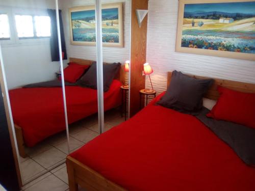 - une chambre avec 2 lits et des draps rouges dans l'établissement T2 Les pieds dans l'eau vue Front de mer, à Saint-Cyprien