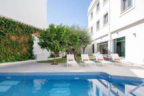uma piscina com espreguiçadeiras ao lado de um edifício em Hotel Infanta Leonor em Écija