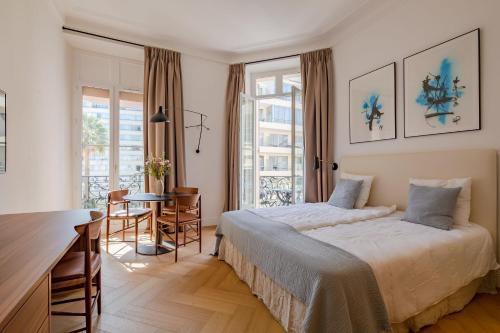 une chambre avec un lit, une table et des chaises dans l'établissement La Guitare 23 - Large modern studio with balcony in center of Cannes, just behind Grand Hotel, à Cannes