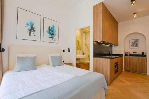 une chambre avec un grand lit blanc et une cuisine dans l'établissement La Guitare 23 - Large modern studio with balcony in center of Cannes, just behind Grand Hotel, à Cannes