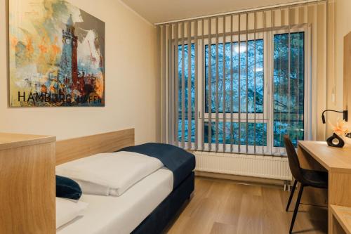 um quarto com uma cama, uma secretária e janelas em MYKY Hotel Boardinghouse em Hamburgo