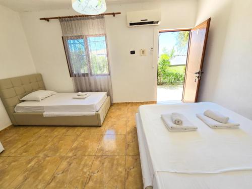1 dormitorio con 2 camas y puerta a un patio en Cozy Hotel Dhermi en Dhërmi