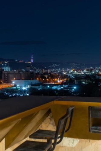 a pair of chairs sitting on a ledge at night at Cozy apartment with a beautiful view of old town in Tbilisi City