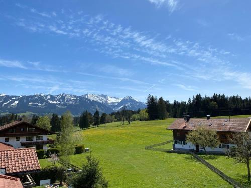 a house in a field with mountains in the background at Bergbauernhof Wechs in Ofterschwang