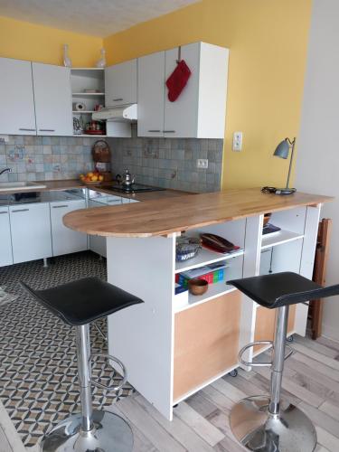 une cuisine avec des placards blancs et deux tabourets de bar dans l'établissement Au cœur du coeur, à Andernos-les-Bains