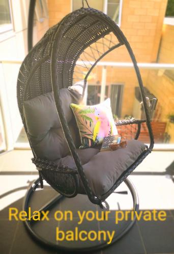 a wicker swing chair with a pillow on a porch at King on Sturt in Adelaide