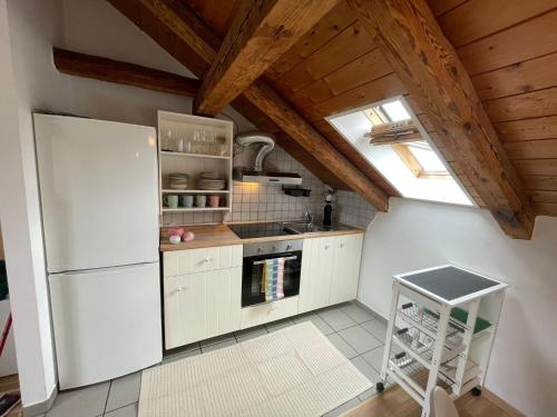 a kitchen with white appliances and a wooden ceiling at BullsLiving Seeapartment 6 Am Corso in Velden am Wörthersee