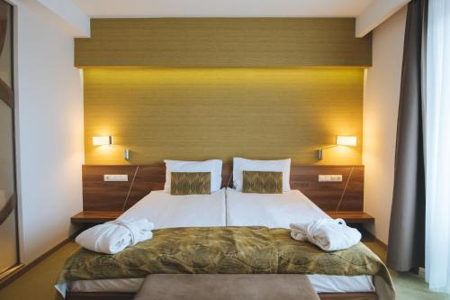 a bedroom with a bed with two towels on it at Imola Hotel Platán in Eger