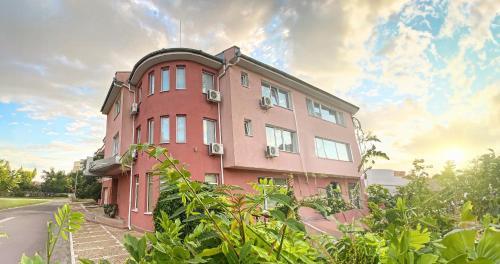 un bâtiment rose sur le côté d'une route dans l'établissement Family Hotel Mania, à Stara Zagora