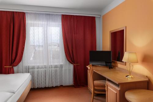a hotel room with a desk with a bed and a window at Savoy Spa & Kurhotel in Františkovy Lázně