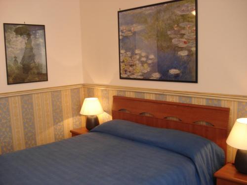 ローマにあるB&B La Bella Giulianaのベッドルーム1室(ベッド1台、ランプ2つ、絵画付)