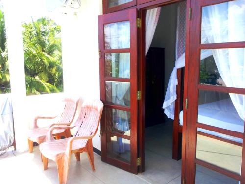 a room with two chairs and a bed on a balcony at Ceylon Surf Guest and Restaurant in Weligama