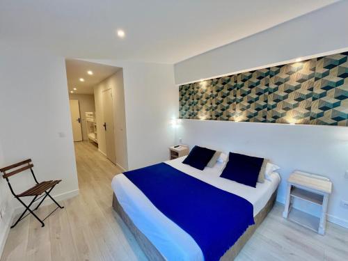 サン・ラファエルにあるオテル ド フロールの青いベッドと椅子が備わるホテルルームです。