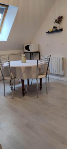 Cette chambre comprend une table, des chaises et un piano. dans l'établissement Le Ptit Normand entre Ville & Plages, à Loucelles