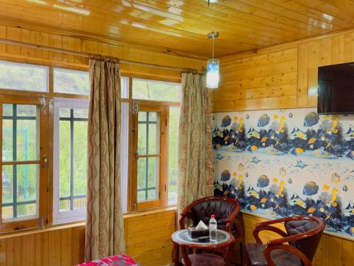 パハルガムにあるLidder Front Resort By Stay Patternのテーブル、椅子2脚、テレビが備わる客室です。