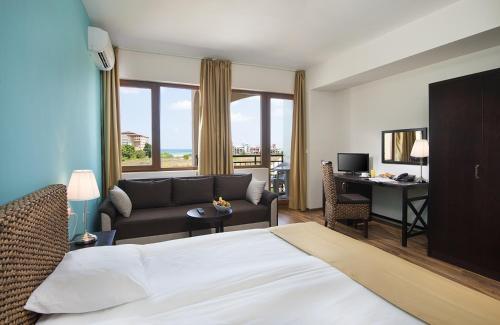 a hotel room with a bed and a couch and a desk at Sunrise All Suites Resort- All Inclusive in Obzor