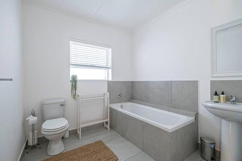a bathroom with a tub and a toilet and a sink at The River House - Addo Elephant Park in Gqeberha